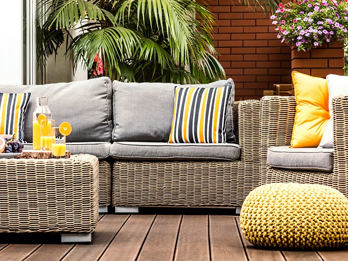 Patio woven furniture in gray with gray cushions and yellow accent throw pillows